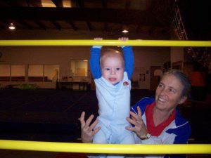 Michele helps am infant play on the uneven bars