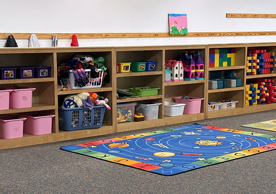 Preschool classroom cubbies neatly filled with bins, books, toys, and building blocks at Carolina Gymnastics Academy.