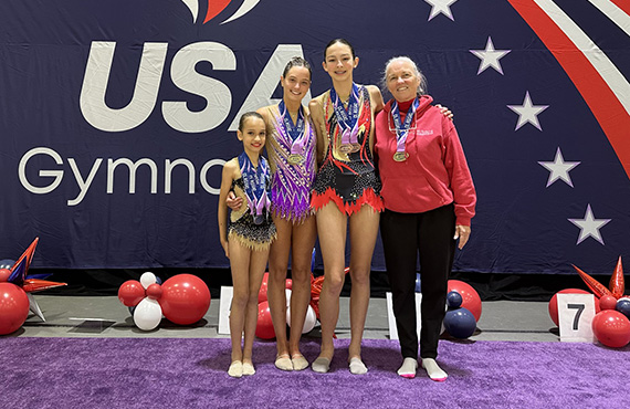 rt3 Three CGA rhythmic gymnasts pose with medals and their coach after winning at a USA Gymnastics meet.