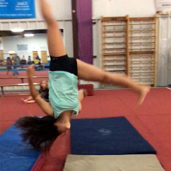 tumbl1 A gymnast mid-back handspring lands on padded mats during tumbling practice at Carolina Gymnastics Academy.